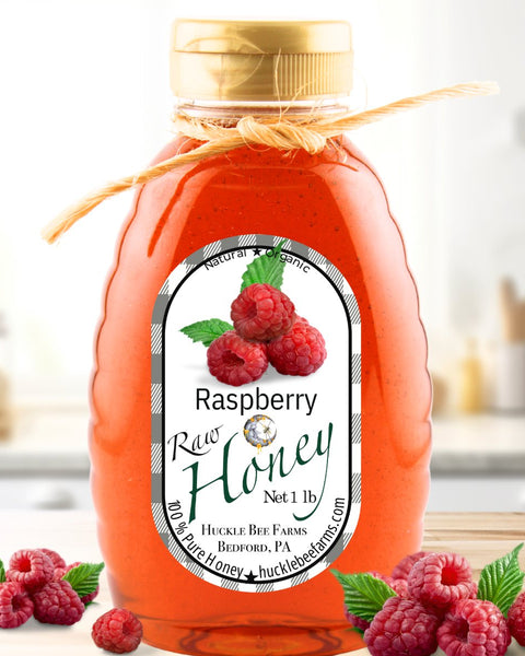 Raspberry infused honey in a 1 lb jar with a natural twine bow, featuring a rich red hue and fresh raspberries, perfect for teas and desserts.