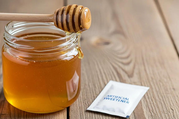 Organic honey jar with wooden dipper and artificial sweetener packet on rustic background