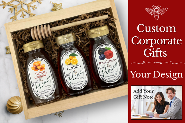 Corporate holiday gift box from Huckle Bee Farms filled with honey jars, pine sprigs, and a thank-you note on a rustic wooden table — sustainable business gift idea.
