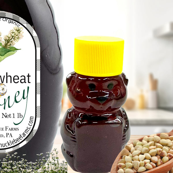 Dark raw buckwheat honey in a bear-shaped bottle with a yellow cap, alongside buckwheat grains, ideal for natural sweetening.