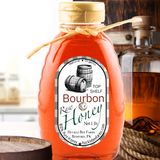 Bourbon Honey bottle surrounded by bourbon barrel wood and a glass of bourbon, ideal for cocktails, glazes, and gourmet recipes.