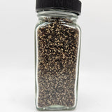 Chef's Grind Black Pepper in clear glass jar with black lid, showcasing coarse Tellicherry pepper perfect for meats, vegetables, and daily seasoning.