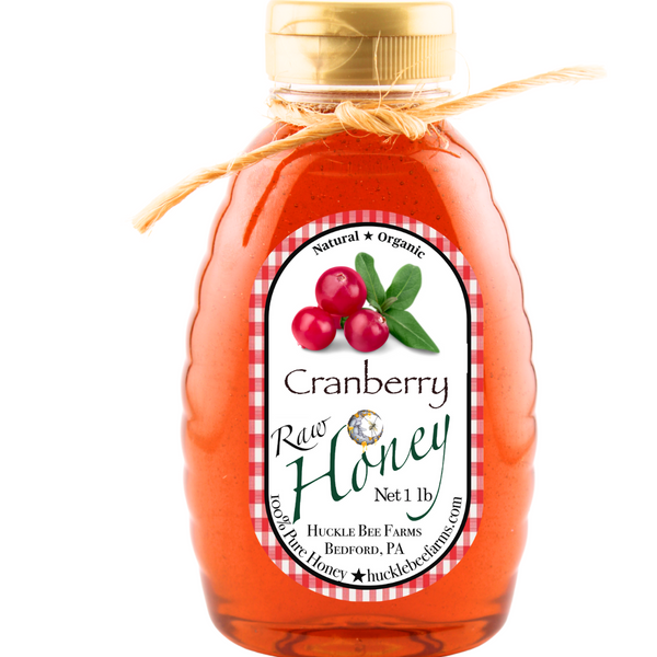 Bottle of cranberry raw honey with a label on a white background