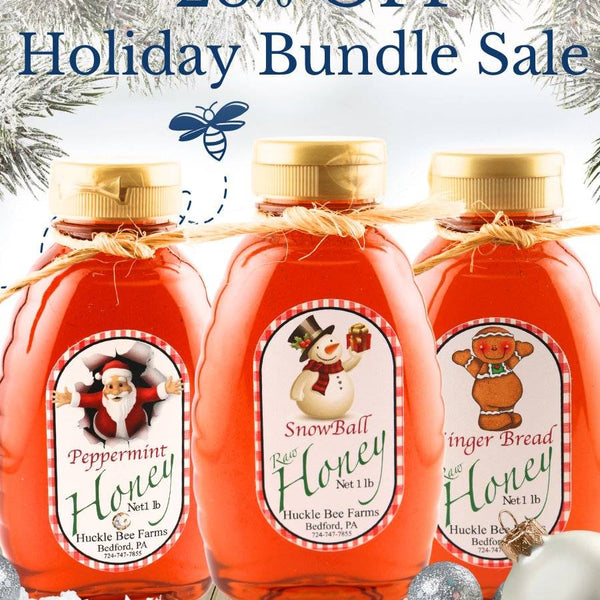 Three bottles of honey with Christmas-themed labels on a snowy background with holiday decorations.