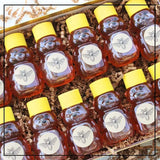 Honey Sampler Gift Box featuring multiple mini bear-shaped bottles filled with golden honey, ideal for gifting and tasting a variety of flavors.