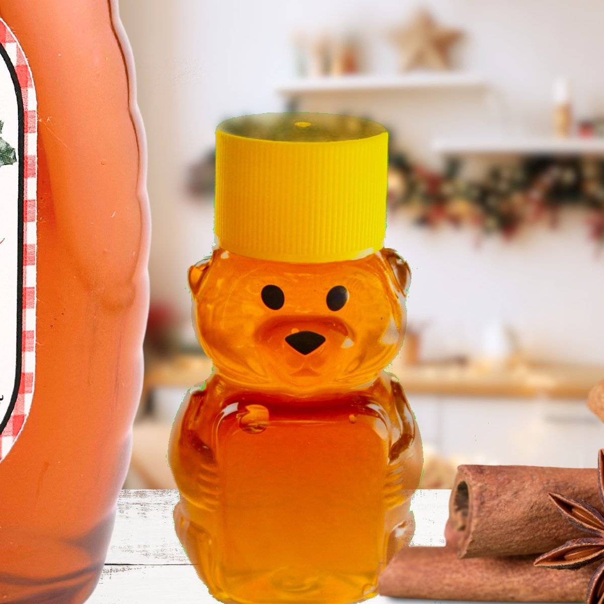 Christmas Magic Honey in festive bear-shaped bottle with yellow cap, surrounded by cinnamon sticks in a holiday-themed kitchen setting.