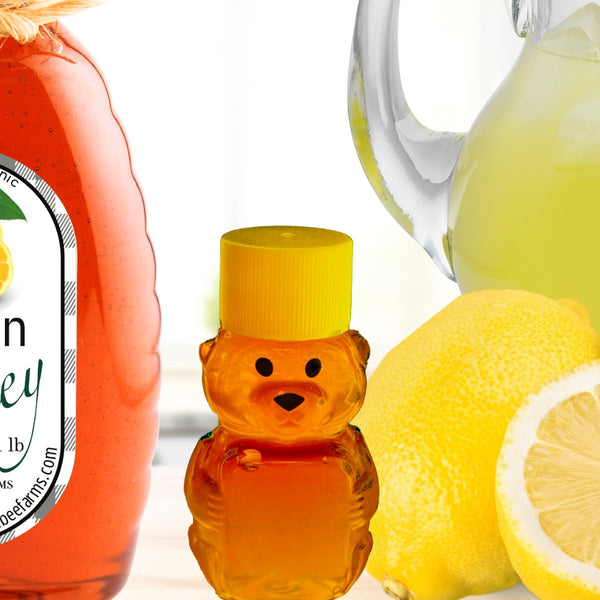 Lemon honey in a bear-shaped bottle alongside fresh lemons and lemonade, emphasizing its organic and flavorful infusion.