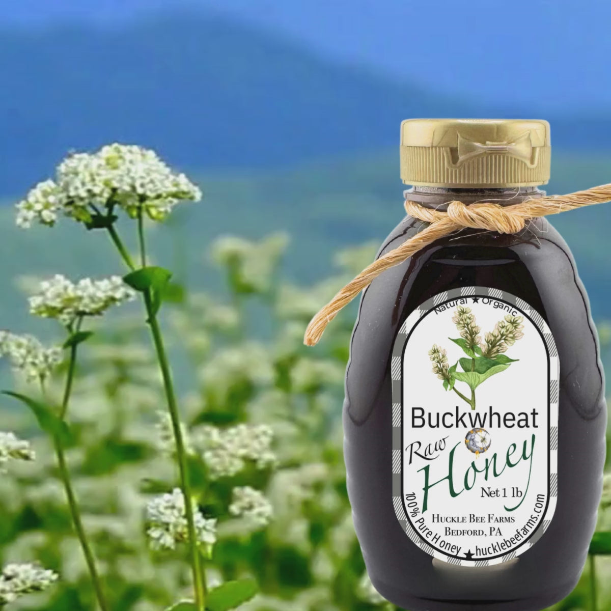 Bottle of raw buckwheat honey set against a blooming buckwheat field, showcasing its natural and organic origins with a deep, robust flavor.