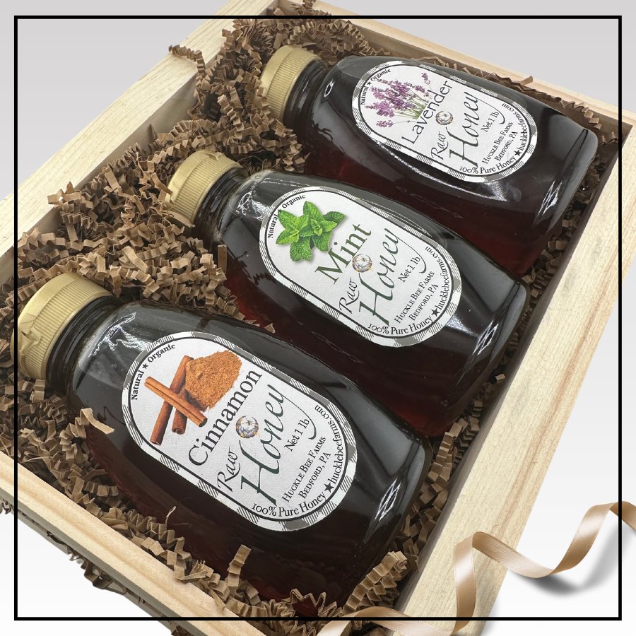 Three-bottle honey gift set in wooden crate with shredded paper