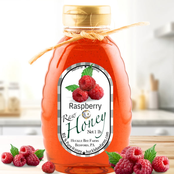 Raspberry infused honey in a 1 lb jar with a natural twine bow, featuring a rich red hue and fresh raspberries, perfect for teas and desserts.