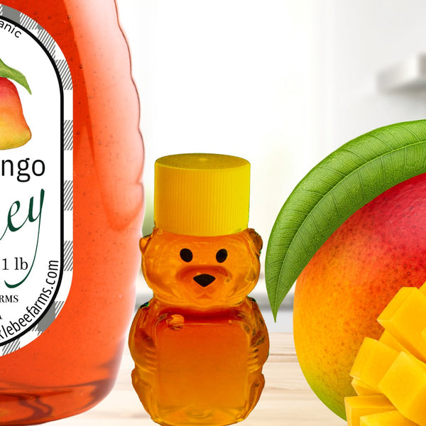 Spicy Mango Honey bottle next to a small bear-shaped honey container and fresh mango slices, highlighting its sweet and spicy infusion.