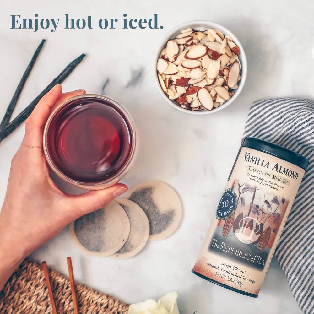 A cup of brewed Vanilla Almond Black Tea with tea bags, almonds, and vanilla sticks, highlighting its smooth and aromatic flavor.