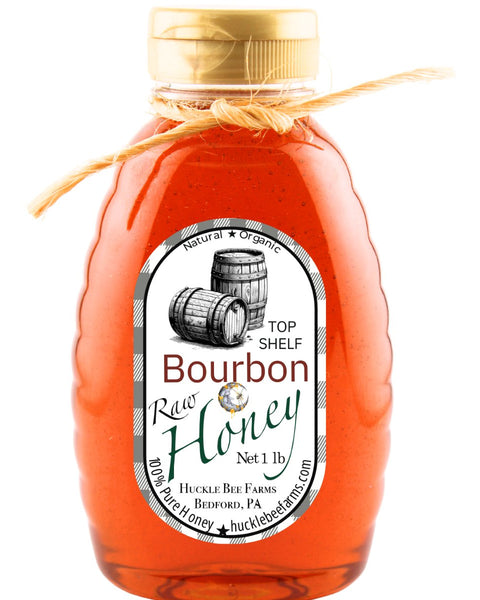 1 lb bottle of Bourbon Infused Honey by Huckle Bee Farms LLC, featuring raw organic honey with a bourbon barrel label design and twine-wrapped cap.