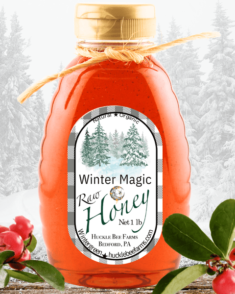 Winter Magic Honey by Huckle Bee Farms LLC in a 1lb jar with a natural and organic label, set against a snowy forest background.