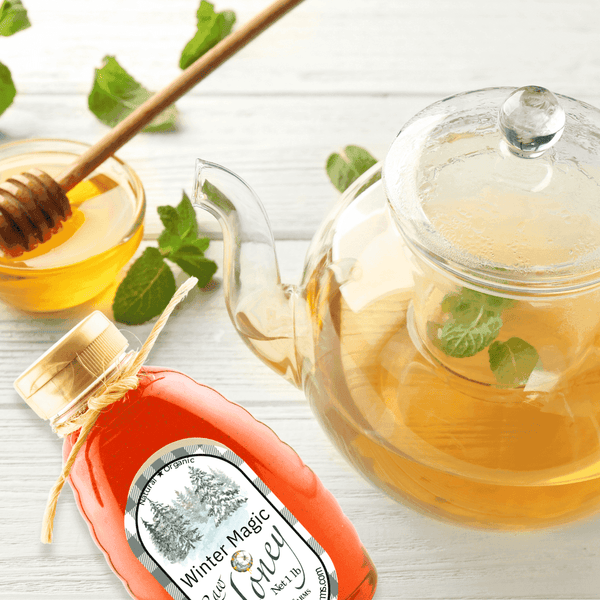 Winter Magic Honey paired with a glass teapot of mint tea. A refreshing wintergreen-infused honey ideal for enhancing tea and desserts with a unique flavor.